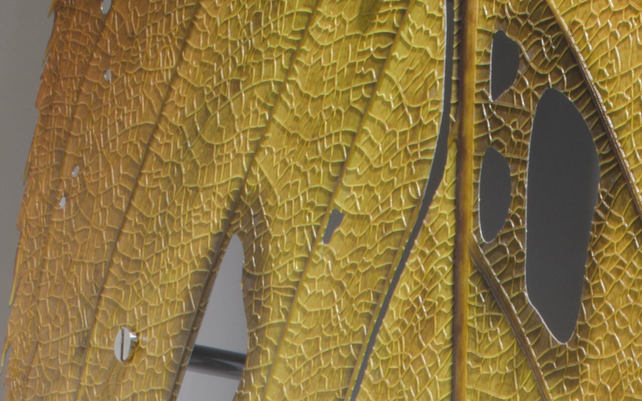 「４features」と名付けられたこの巨大な葉は日鉄日新製鋼株式会社様の開発品である「高意匠イクジェット印刷鋼板」を用いたオブジェであり、  インクジェット印刷鋼板の４つの技術的特徴を活かすことで造られています。